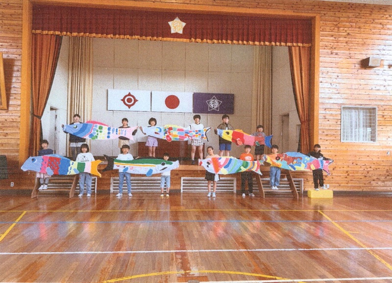 体育館でカラフルなこいのぼりを掲げる子どもたち