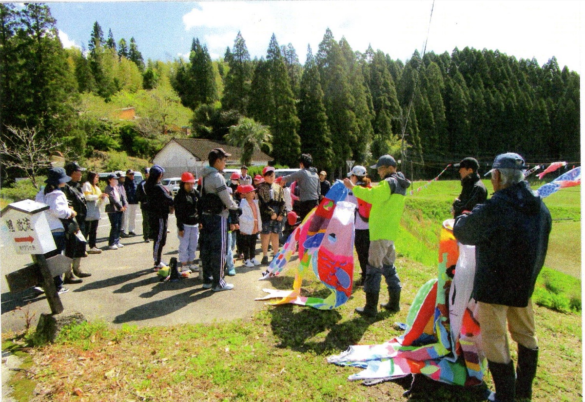 児童と地域住民がこいのぼりを掲揚する様子