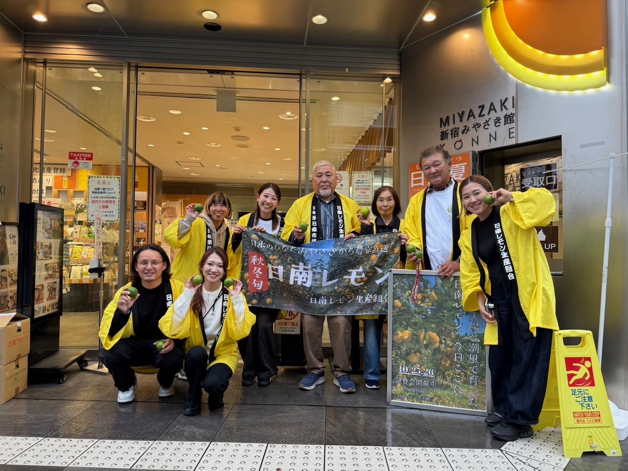 新宿みやざき館KONNE前での記念撮影。黄色はっぴ姿のスタッフが日南レモンを手に