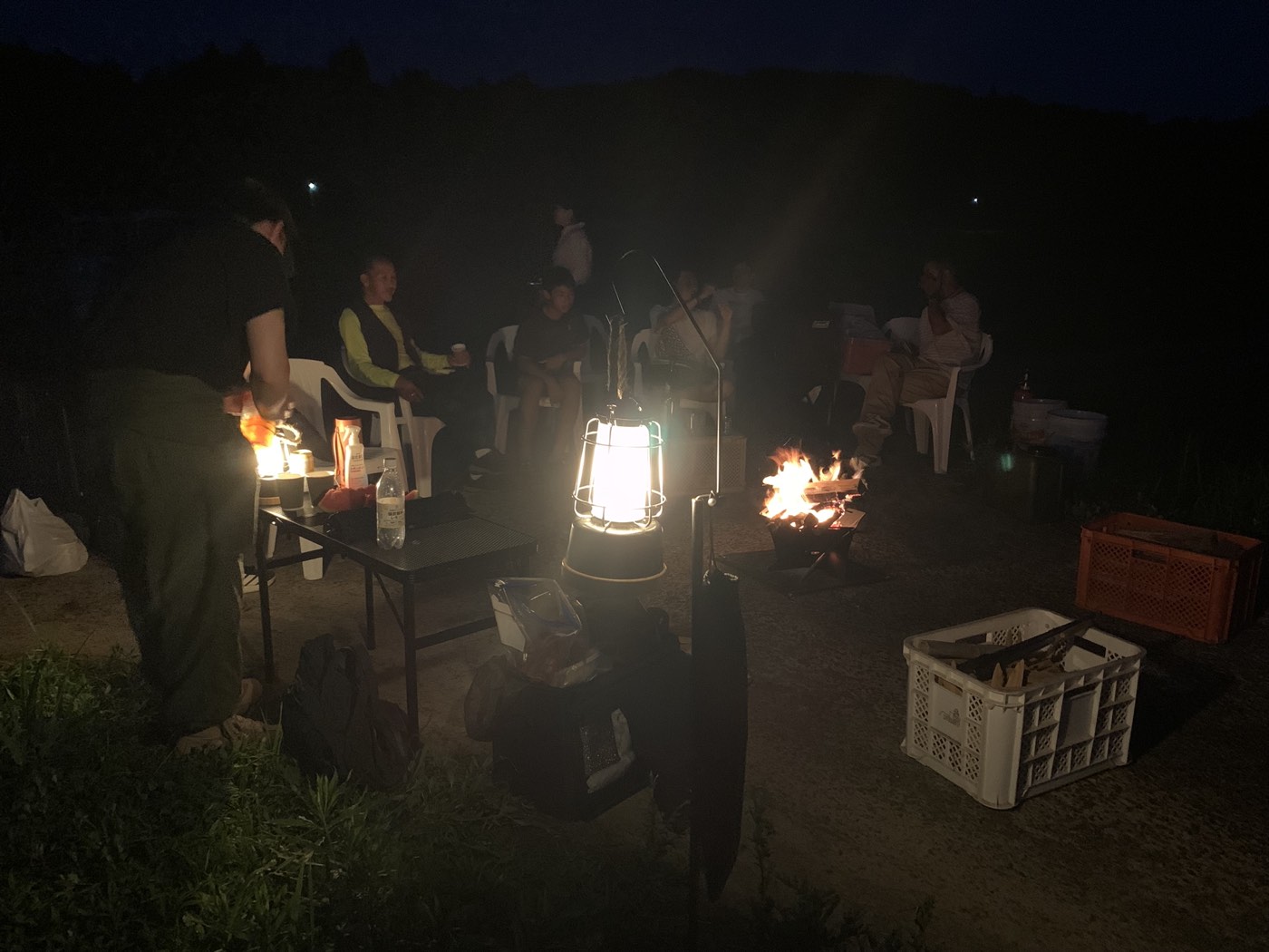 夜、ランタンの灯りに照らされる焚き火の輪