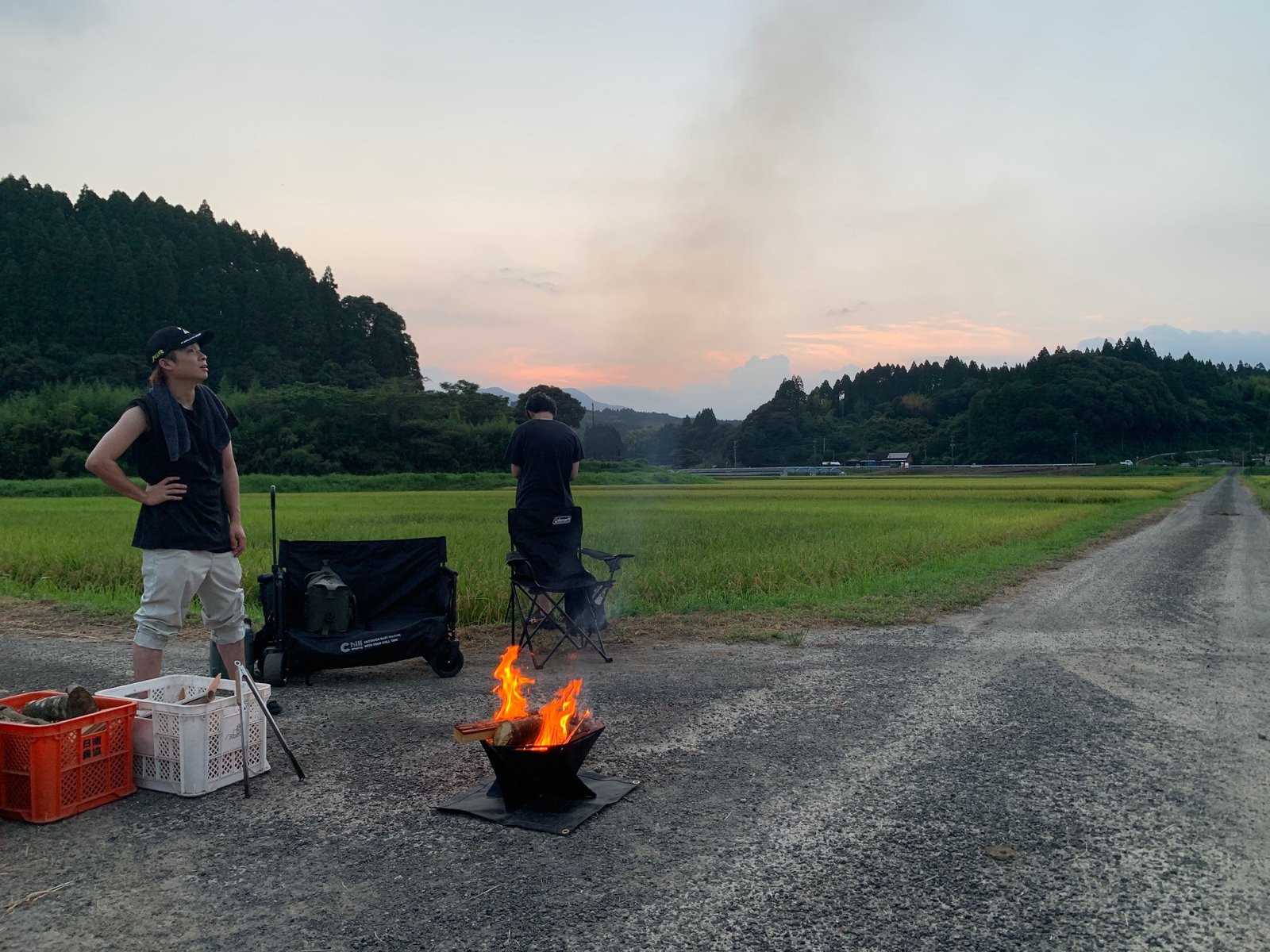 夕景の中、焚き火に火が入り煙が立ち上る様子