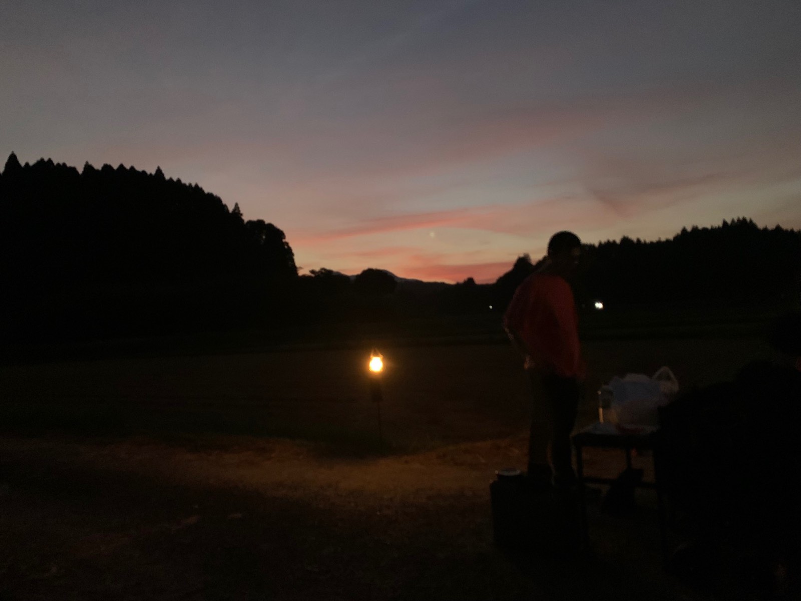 茜色に染まる夕焼けとランタンの灯り、たたずむ参加者のシルエット