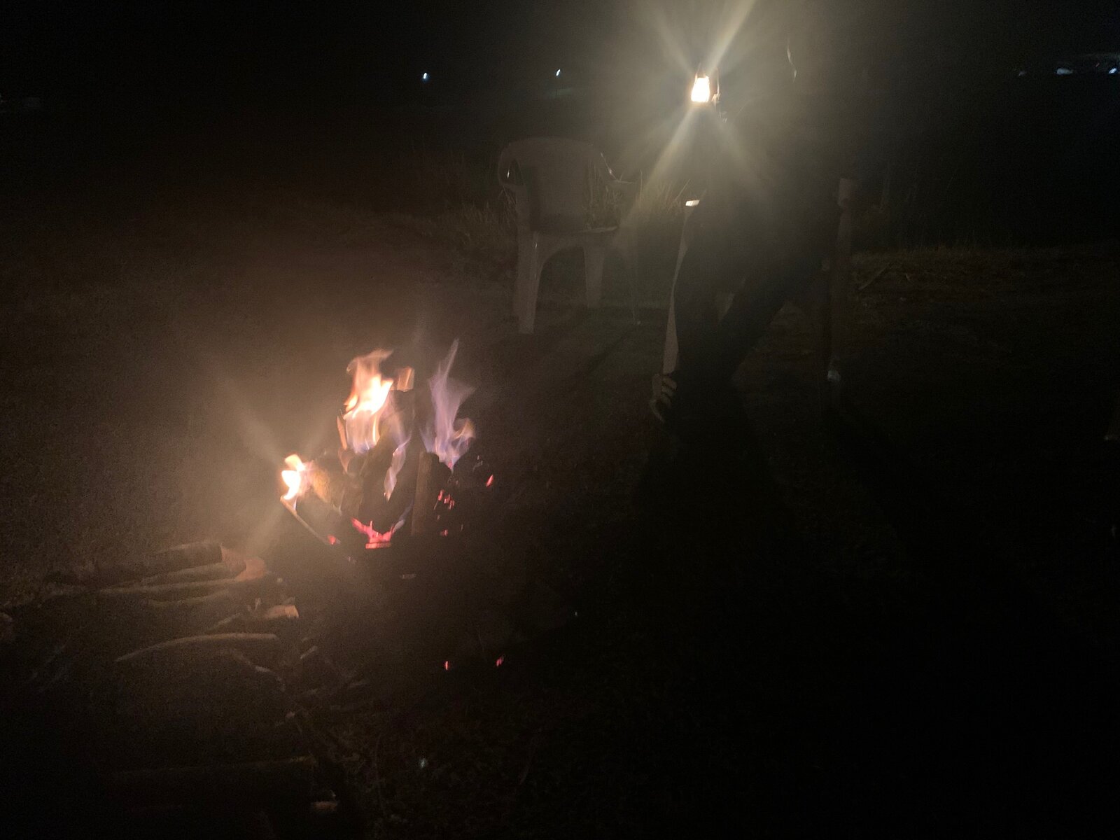 ランタンの灯りと椅子が並ぶ夜の会場、静かに燃える焚き火
